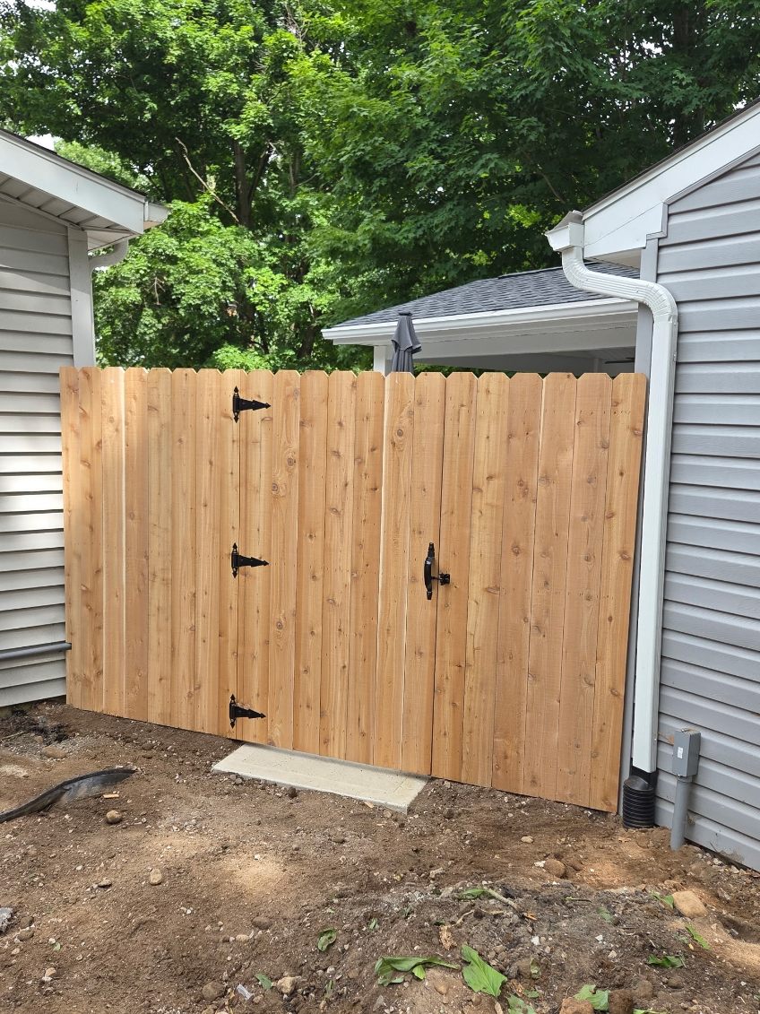 New cedar privacy fence with double gate and black hardware between two homes
