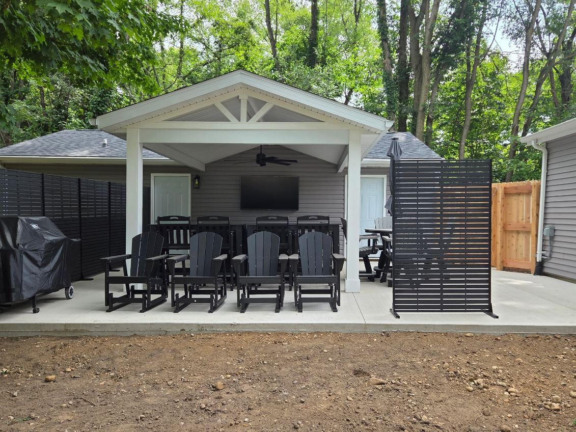 Backyard pavilion with white gable roof, open trusses, ceiling fan and mounted TV over a concrete patio built by T&J Construction