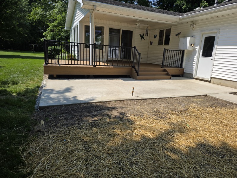 Composite deck with black aluminum railing and steps leading to a new concrete patio pad built by T&J Construction